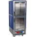 A blue and silver Metro C5 heated holding and proofing cabinet with clear Dutch doors on a shelf.