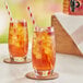 Two glasses of Bromley iced tea with straws and ice on a table.