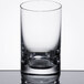 A close up of a Stolzle New York tumbler filled with a small amount of liquid.