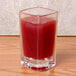 A Thunder Group plastic square dessert shot glass with red liquid in it on a table.