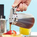 a person pouring liquid into a fruit