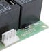 A close-up of a white and black circuit board inside a black box with two wires.
