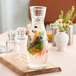 A Libbey glass carafe filled with water and fruit on a wooden board.