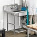 A man washing dishes in a stainless steel sink in a commercial kitchen.