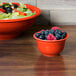 A Fiesta bouillon bowl filled with blueberries and raspberries on a table with a bowl of fruit.