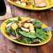 A Fiesta china platter with salad and a fork on a table with a glass of soda.