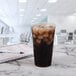 A Solo Ultra Clear plastic cup filled with ice tea on a table next to a notebook and pen.