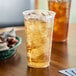 A Solo Ultra Clear plastic cup filled with iced tea on a table.