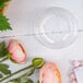 A clear plastic dome lid with a hole on a clear bowl with pink flowers.