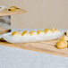 A white American Metalcraft Translucence bowl with sliced bread in it on a table.