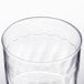 A close up of a Fineline clear plastic wine cup with a wavy design.