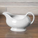 A Fiesta white China gravy boat on a wood surface.