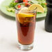 A Libbey stackable beverage glass with iced tea and lemon slices with a lemon wedge on the rim.