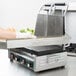 A person using a Waring drip tray to cut a sandwich on a counter.