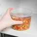 A hand holding a Solo MicroGourmet deli container of food.