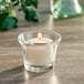 A Sterno candle in a glass holder on a table.