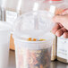 A hand holding a Solo clear plastic container with pasta in it.