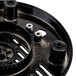 A black circular metal plate with holes.