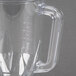 A clear plastic blender jar with a handle.