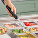A hand holding a black Vollrath Spoodle over a bowl of food.