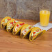 American Metalcraft stainless steel taco holder with tacos on a table.