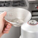 A person using a Waring stainless steel strainer on a juicer.