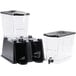 Two Carlisle black plastic beverage dispensers with clear containers and black lids.