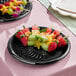 A black plastic catering tray holding assorted fruit skewers.