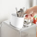 A hand holding a cup with white Steril-Sil flatware in it.