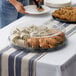 A woman using a Visions clear plastic catering tray high dome lid to serve sandwiches on a table outdoors.