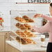 A woman putting pastries in a Choice bakery display case.