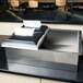 A Steril-Sil stainless steel flush-mount silverware dispenser on a black counter.