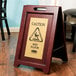 A Rubbermaid Executive wet floor sign on a wood floor.