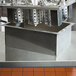 A Steril-Sil stainless steel drop-in silverware dispenser on a counter in a school kitchen.