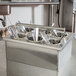 A Steril-Sil stainless steel drop-in silverware dispenser with utensils inside.