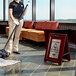 A woman using a Rubbermaid Executive Wet Floor Sign to clean the floor in a corporate office.