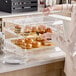 A woman putting pastries in a Choice Bakery Display Case.