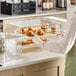 A person holding a Choice Bakery Display Case tray of pastries on a counter in a bakery display.