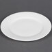 A CAC white bone china plate with a small rim on a gray surface.