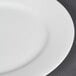 A close-up of a CAC Majesty European Bone China round plate with a white rim.