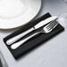 A knife and fork on a black Hoffmaster linen-like napkin.