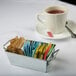 A cup of tea with a tea bag in a small metal American Metalcraft sugar caddy.