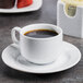 A CAC Boston Super Bright White porcelain cup of coffee on a saucer.