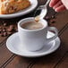 A person spooning coffee into a Diamond White espresso cup.