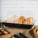 A polycarbonate cover on a basket of bagels and muffins on a counter in a bakery.