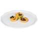 A white round melamine display platter with fruit tarts on it.