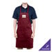 A man wearing a burgundy Chef Revival apron with a purple logo standing at a counter in a professional kitchen.