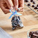 A person tying a blue ribbon around a bag of chocolates.