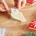 A person putting a heart-shaped cookie in an LK Packaging plastic candy bag.