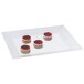 A white rectangular melamine display tray with cakes frosted in red and black with white dots.